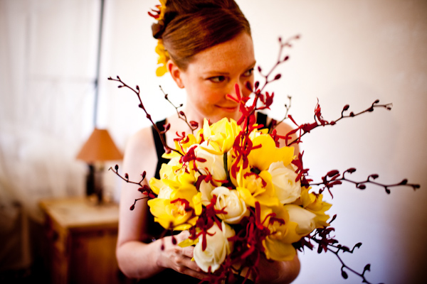 bridesmaid holding a beautiful yellow, ivory, coral, and dark red floral bouquet - photo by New Mexico based wedding photographers Twin Lens